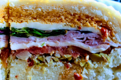 Homemade-uncured-ham-Calabrian-chili-giardiniera-Muffuletta-on-fresh-boule-crisp-and-fresh-waffle-fries-with-from-scratch-roasted-red-pepper-aioli-and-cured-olives